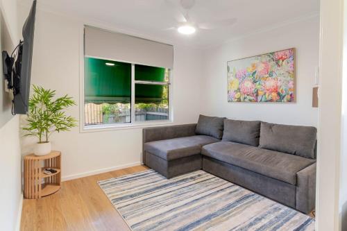 a living room with a couch and a window at Botanic Base - Designed for Ease & Comfort in Wagga Wagga