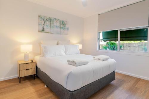 a bedroom with a large white bed and a window at Botanic Base - Designed for Ease & Comfort in Wagga Wagga