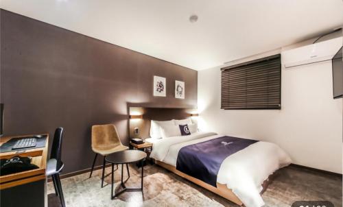 a hotel room with a bed and a desk and chair at 엘루이호텔 in Busan