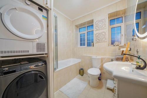 a bathroom with a washing machine and a sink at Spacious Modern 3 Bed Apartment in Hendon NW4 in Colindale