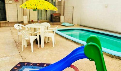 a pool with a table and chairs and an umbrella at Casa de Hóspedes Kipper in São Gabriel