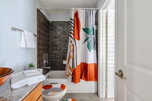 a bathroom with a toilet and a shower curtain at Fireside Double Kings Midtown Luxe Suite in Houston