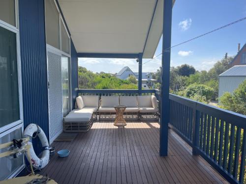 a porch with a couch and a table on a balcony at La Sirena, Venus Bay in Venus Bay
