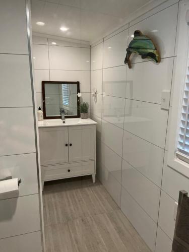 a white bathroom with a sink and a mirror at Portobello Bach Double Cove in Lochmara Bay