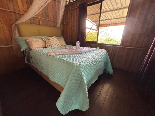 een bed met een groen dekbed in een kamer bij Mountain Retreat Refugio de Aves in Turrialba