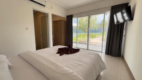 a bedroom with a white bed and a large window at Lushy Kintamani in Kubupenlokan