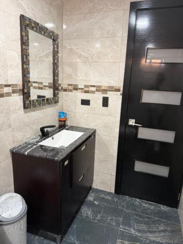 a bathroom with a sink and a black door at Quinta Nallig in Gualaceo