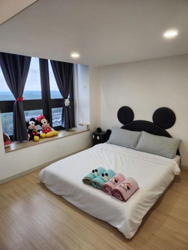 a bedroom with a white bed with three stuffed animals on it at Sunway Grid Mickey House 4-5pax, 8mins to Legoland in Iskandar Puteri