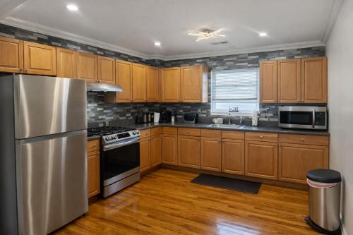 een keuken met houten kasten en een roestvrijstalen koelkast bij Tremont Hidden Treasure in East Orange