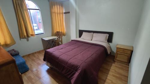 a bedroom with a large bed with a purple blanket at Huachuma Rooms in Huaraz