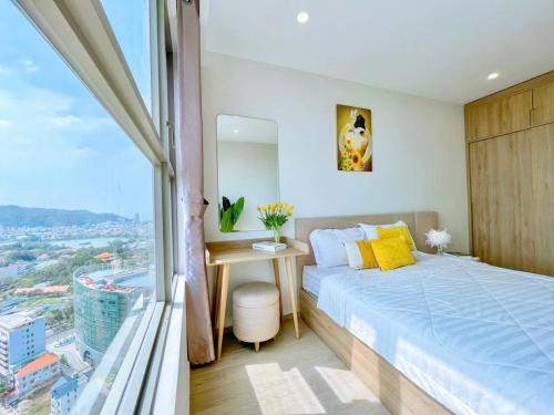 a bedroom with a bed and a desk and a window at The sóng Remy Apartment in Vung Tau