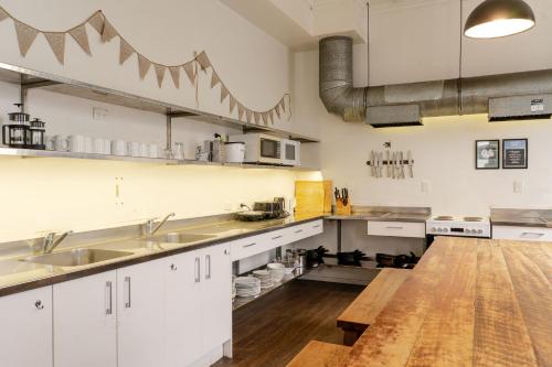 a large kitchen with white cabinets and a wooden floor at Haka House Auckland K'Road in Auckland