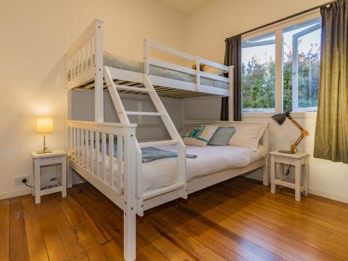 a bedroom with a white bunk bed and a window at Aroha Cottage in Ohakune