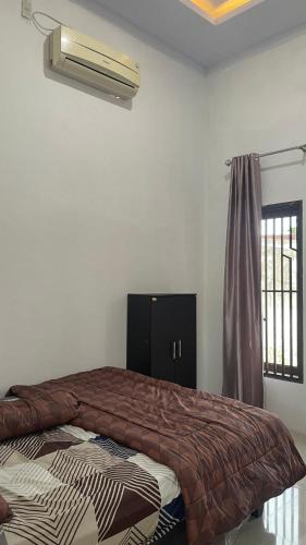 a bedroom with a bed and a air conditioner at Denggan KNO Guest House in Tanjungmorawa