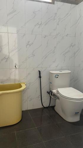 a bathroom with a toilet and a bath tub at Denggan KNO Guest House in Tanjungmorawa