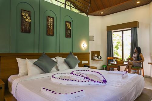 a woman sitting at a table in a bedroom with a bed at Misty Lake Resorts Munnar By Sylora Hotels in Munnar