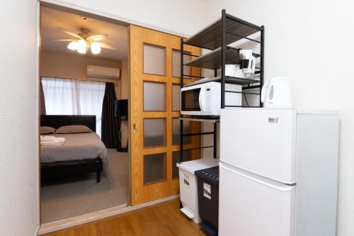 a small room with a refrigerator and a bed at Evergreen hotel ichigaya luxe in Tokyo