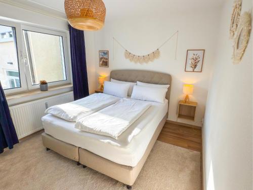 a bedroom with a large white bed with two windows at City Apartments Gerlingen in Gerlingen