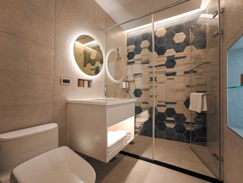 a bathroom with a toilet and a glass shower at Hanpin Homestay in Yuli