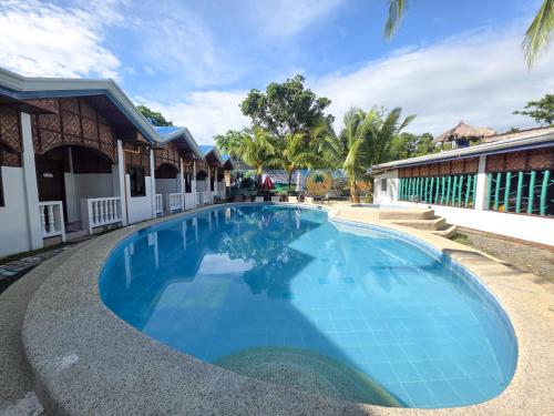 a large blue swimming pool in front of a building at Golden palm rise resort in Libaong
