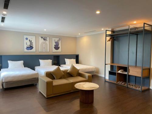 a hotel room with two beds and a couch at Indigen Riverside Hotel Cao Bang in Cao Bằng