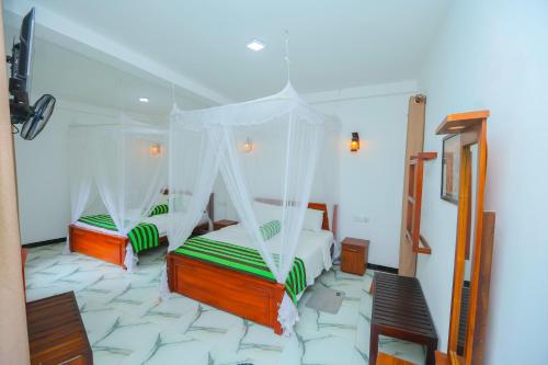 a bedroom with two beds with mosquito nets at Forest Edge Villa in Ella