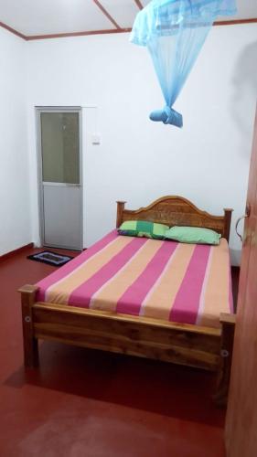 a bed with a colorful striped comforter in a room at Sinharaja Backpacker Homestay in Kandilpana