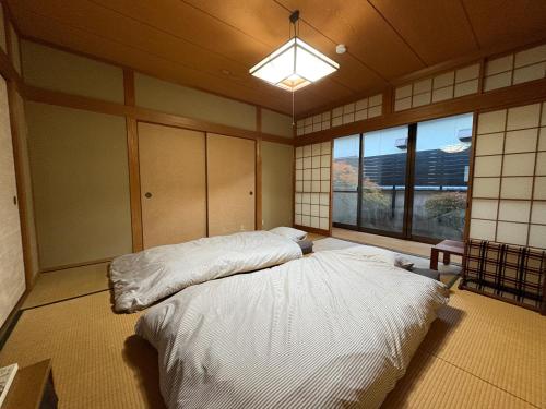 a bedroom with a large bed in a room with a window at ゲストハウス あしもり in Okayama