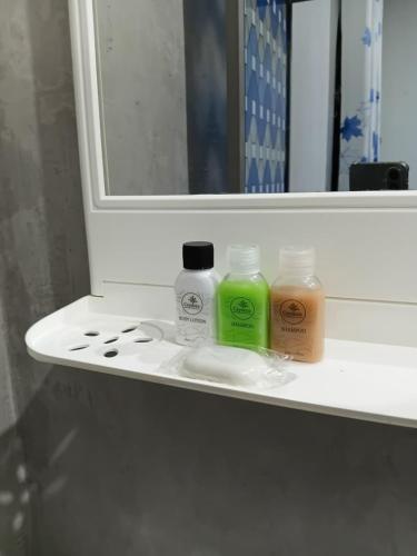 a shelf with three bottles of soap and a mirror at Diyakalana Rest in Ginigathena