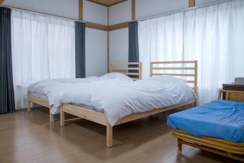 a bedroom with two beds with white sheets and curtains at 伊豆の宿 静川 in Ito