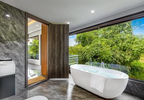 a bath tub in a bathroom with a large window at Ruby Mountain View Resort Vang-vieng in Vang Vieng