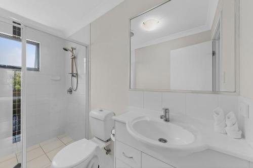 a white bathroom with a toilet and a sink at Mango Hill 3 Bedroom Family Accommodation in North Lakes