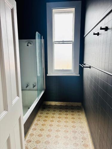a blue bathroom with a shower and a window at Rehutai in Wairoa