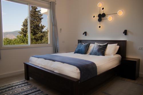 een slaapkamer met een groot bed met een groot raam bij הבית ליד הבוסתן in Mikhmannim