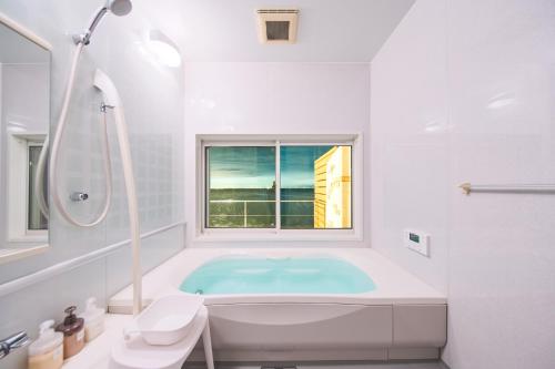a white bathroom with a tub and a window at Villa Acatella in Awaji