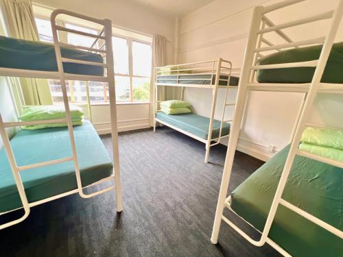 a room with three bunk beds and a window at Utopia31 Hostel - formerly Frienz Backpacker in Auckland