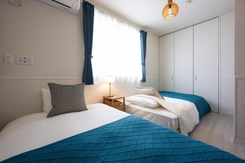 two beds in a room with a window at Matsumoto 101 in Matsumoto