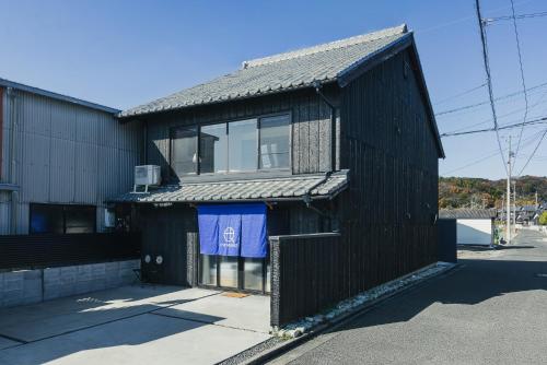 a black building with a blue towel on the side of it at ゲストハウス海窓 in Setouchi
