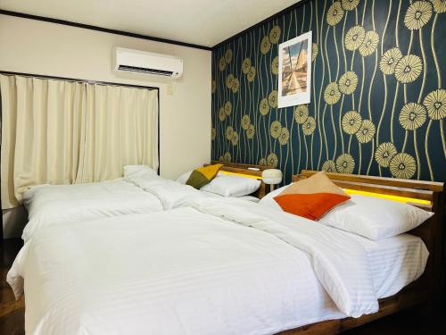 two beds in a bedroom with floral wallpaper at Maison du Skytree Tokyo in Tokyo