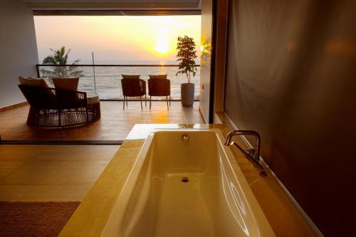 a bath tub in a room with a view of the ocean at Sukavi in Paravūr