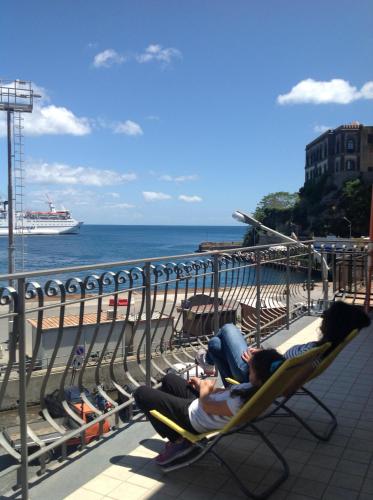 two people sitting in chairs on a balcony looking at the ocean at Bella Vista in Lipari
