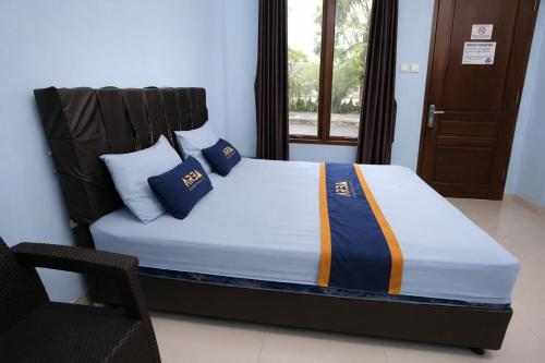 a bed with blue pillows on it in a room at Mekarsari Hotel By ARBA in Tjipitjung Tiga