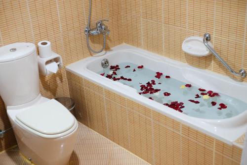 a bathroom with a toilet and a bath tub filled with flowers at Baity Hotel Apartments in Dubai