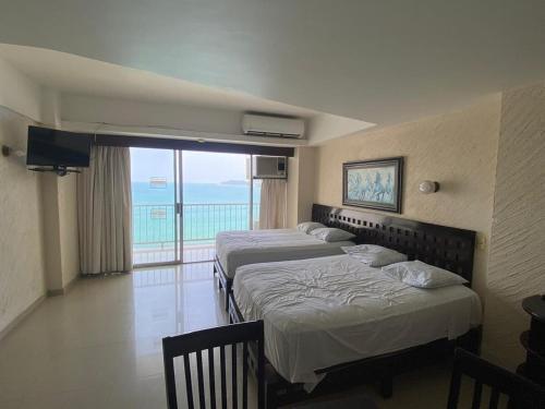 two beds in a room with a view of the ocean at Suite en Torres Gemelas Acapulco piso 19 in Acapulco