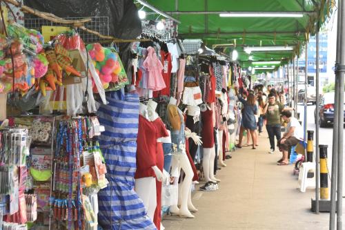 a crowd of people walking past a market with clothes on display at Hide Bangkok Hostel in Bangkok