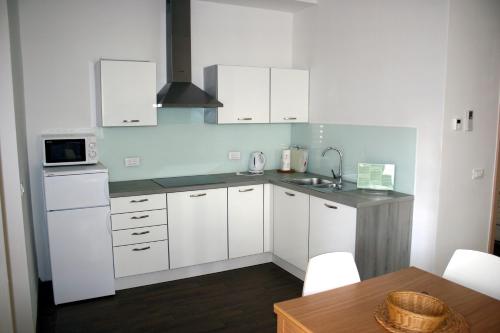 eine Küche mit weißen Schränken, einer Spüle und einem Tisch in der Unterkunft Park Apartments in Izola