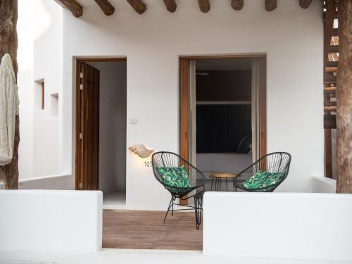 a patio with two chairs and a table at Villas HM Palapas del Mar in Holbox Island