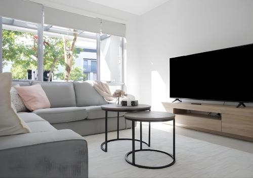 a living room with a couch and a tv at Premier 4BR Seaside Escape & Luxury Steps from Coogee Beach in Sydney