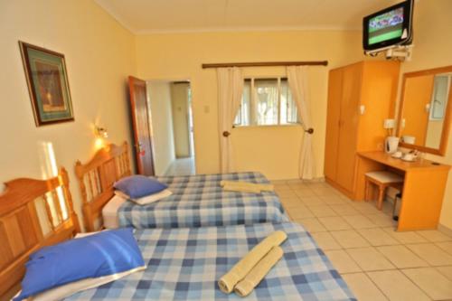 a hotel room with two beds and a television at Schuetzenhaus Guesthouse in Keetmanshoop