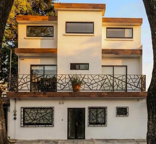 a house with a balcony and two trees at Suites C O V A D O N G A in Mexico City